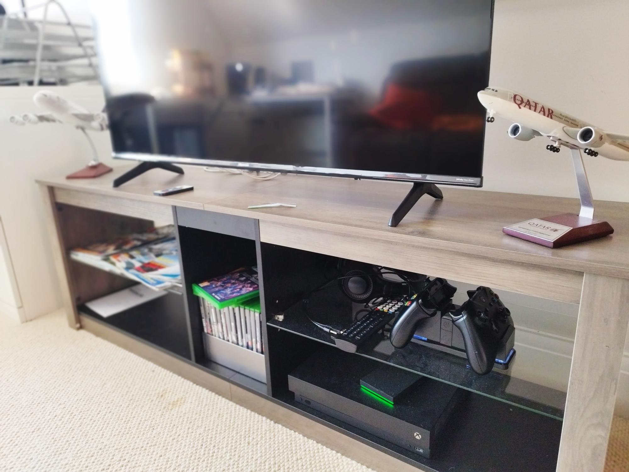 Entertainment centre with TV, games console, controllers, model aircraft and magazines