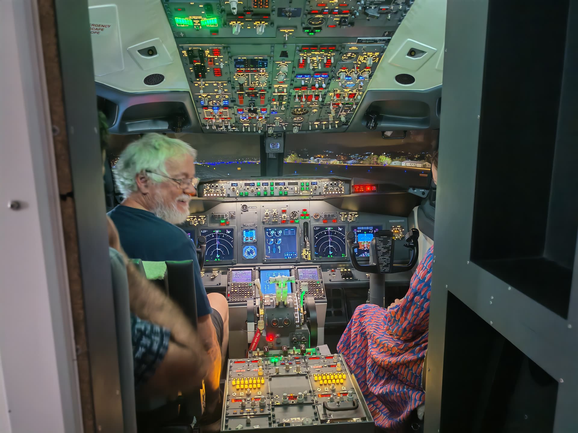 Senior guest in the left seat, cockpit door framing the instrument panel and screens